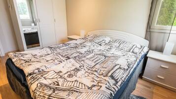 A bedroom with a bed, a nightstand, a dresser, and a window.