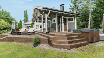 Une maison moderne dotée d’un porche abrité, d’un espace salon extérieur et d’un jacuzzi.