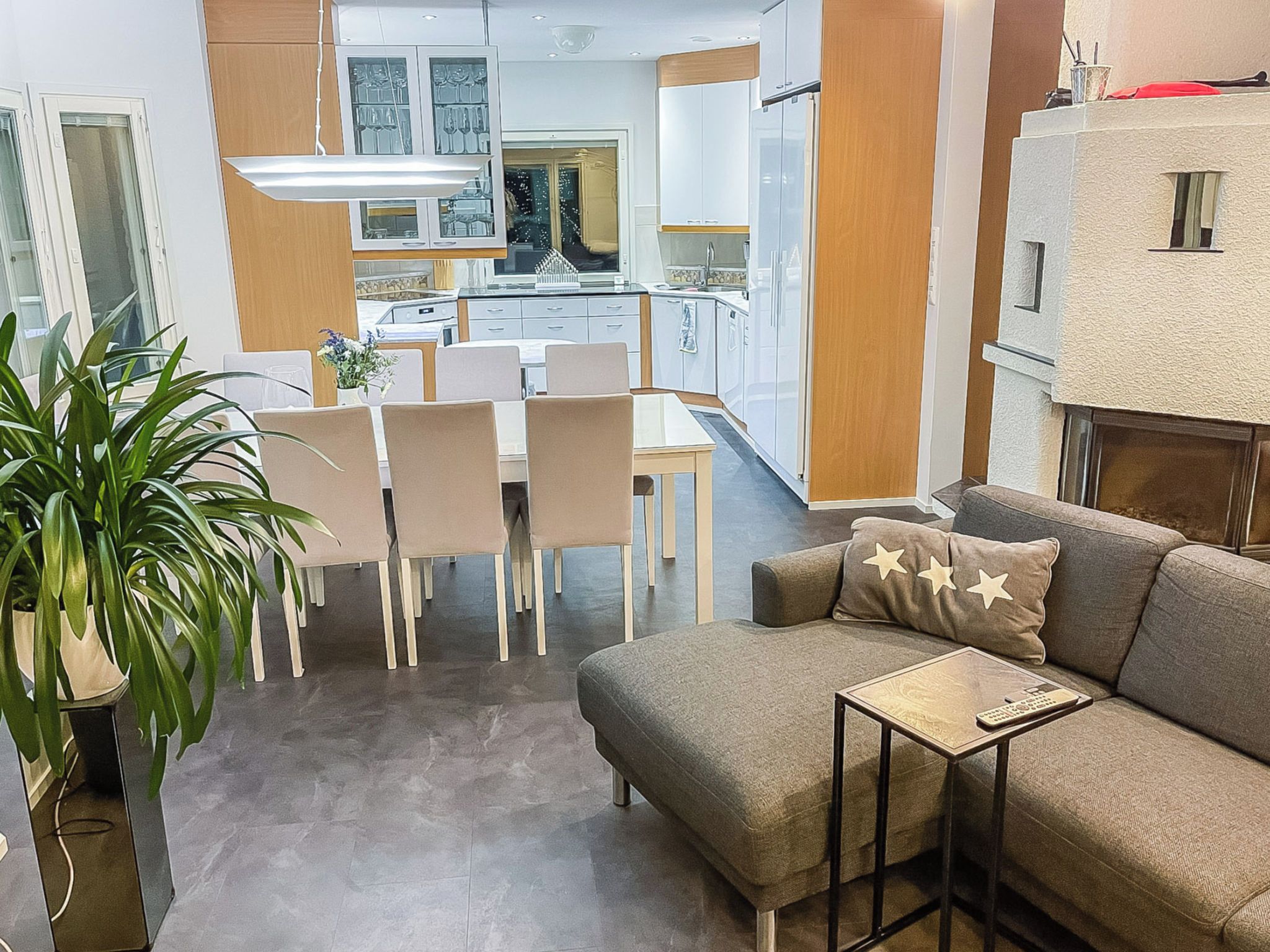 A modern living room with a sofa, a coffee table, and a dining area with chairs and a table.