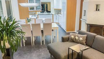 A modern living room with a sofa, a coffee table, and a dining area with chairs and a table.
