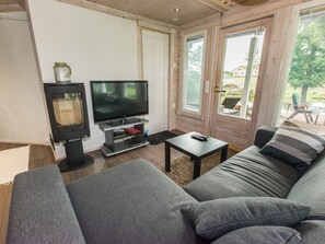 A living room with a sofa, a television, and a small table. - Villa jokiranta by Interhome (Eurajoki)