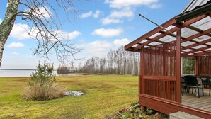 A covered outdoor seating area with a view of a lake and trees.