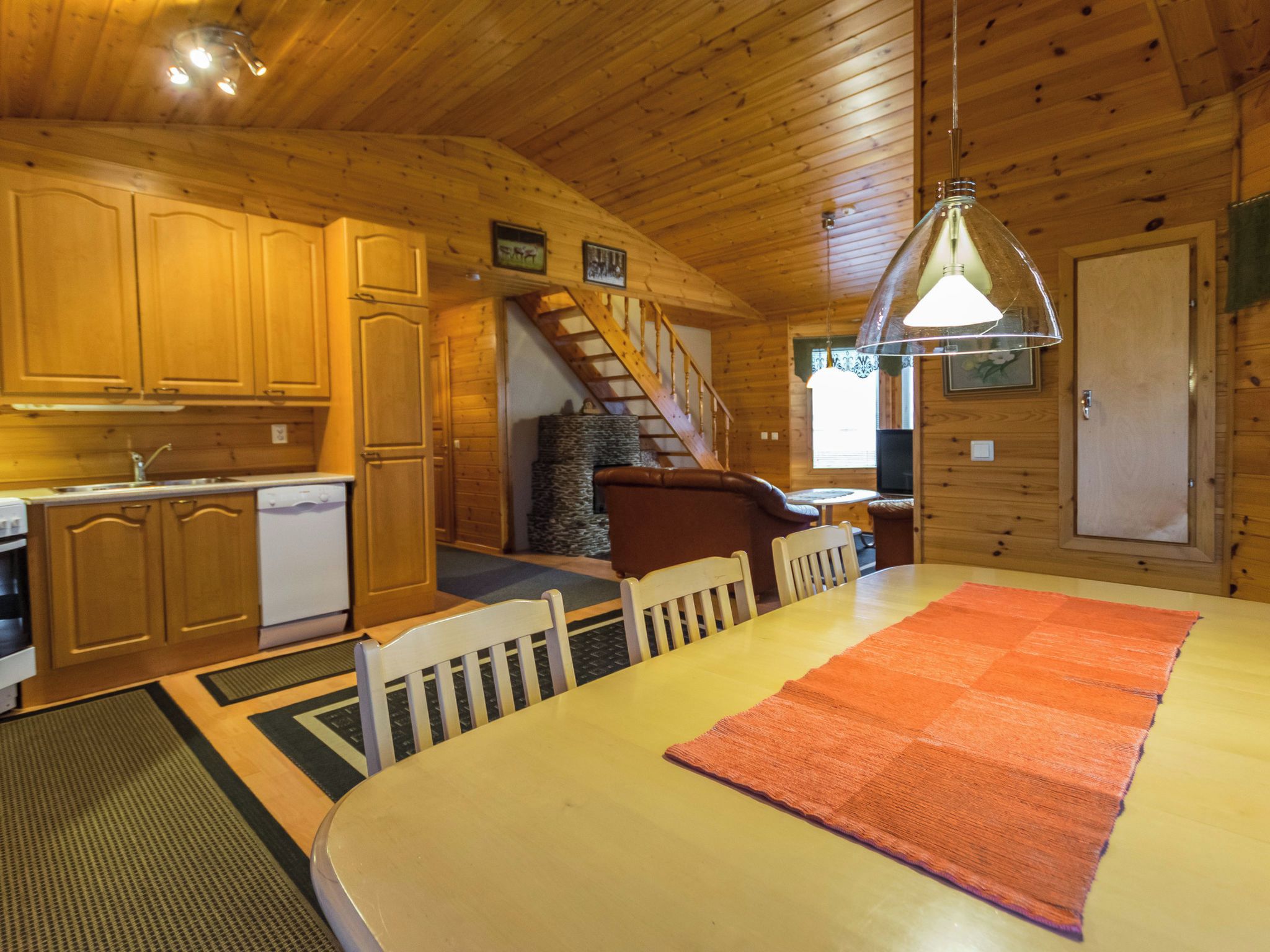 A wooden interior with a kitchen, dining area, and a staircase.