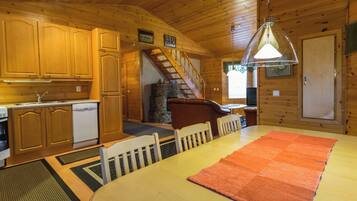 A wooden interior with a kitchen, dining area, and a staircase.