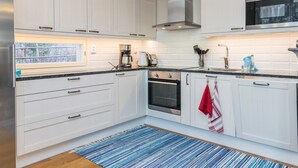 Una cocina moderna con armarios blancos, una campana extractora de acero inoxidable, horno empotrado y microondas.