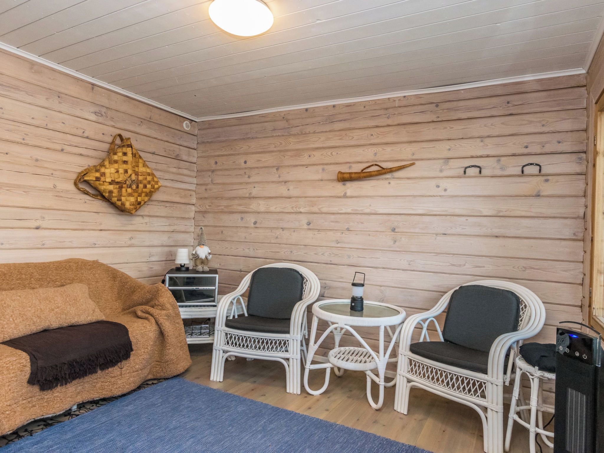 Una habitación acogedora con sofá, dos sillones, una mesita, una lámpara y un adorno en la pared.