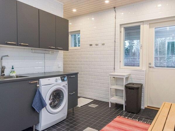 A compact kitchen with a built-in washing machine, a sink, and a window.