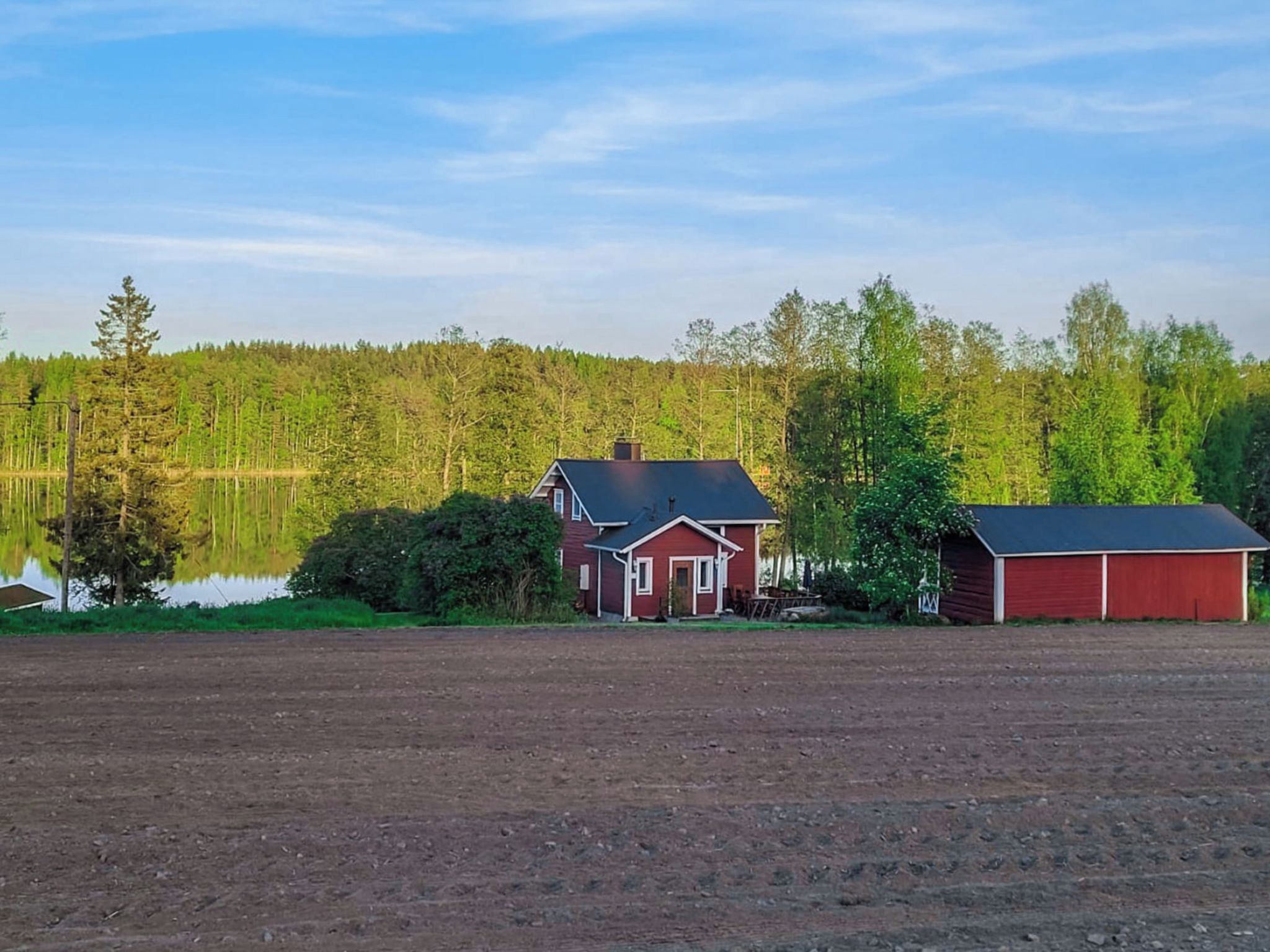 Maaseudulla sijaitseva kiinteistö, johon kuuluu talo, lato ja suuri avoin pelto.