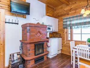 Une cuisine rustique avec une cheminée en briques, des armoires blanches, un four à micro-ondes et un coin repas comprenant une table et des chaises.