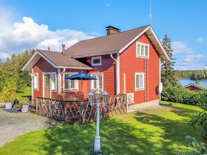 Une maison rouge avec une terrasse, du mobilier d’extérieur et une antenne parabolique.