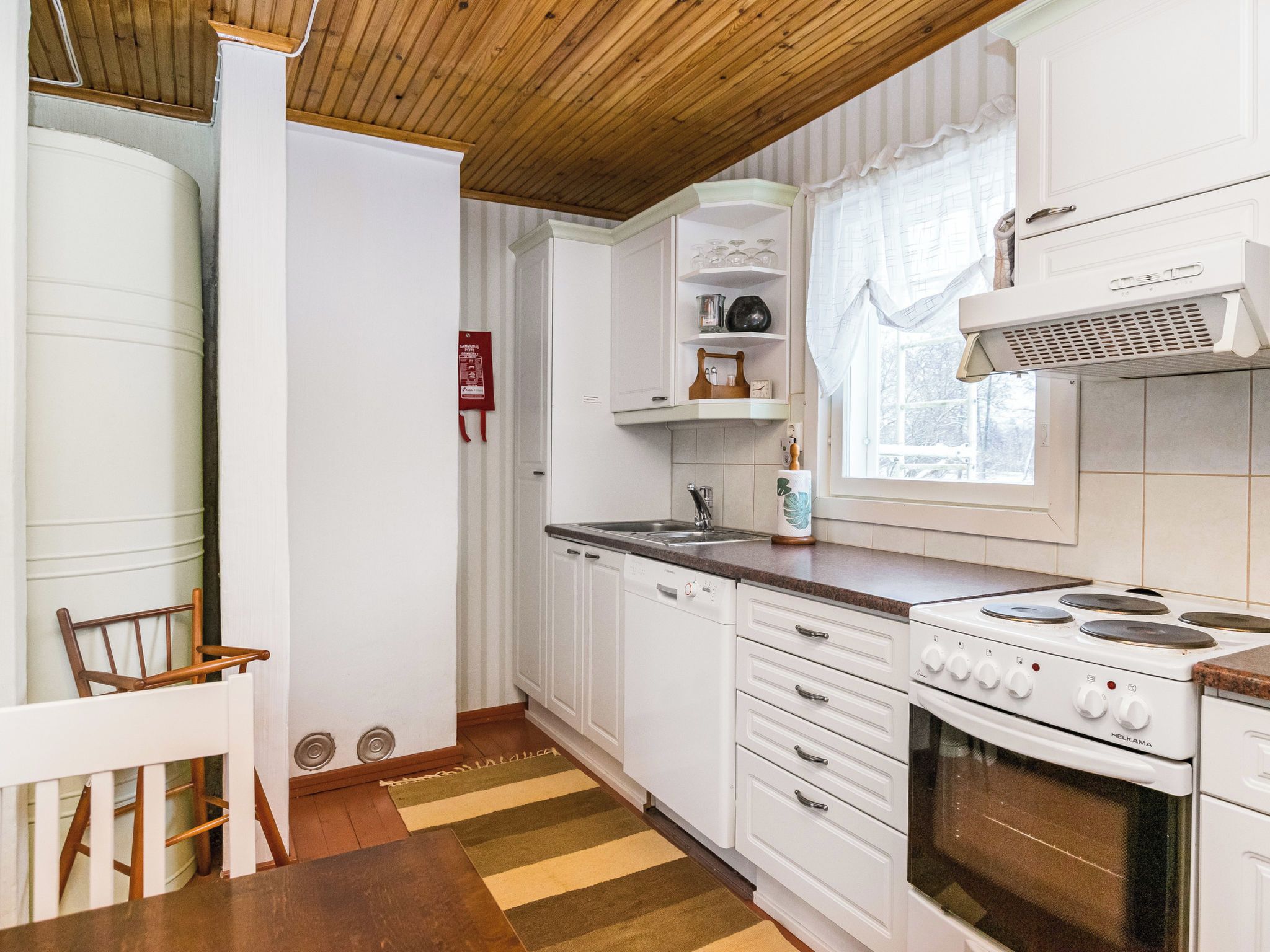 A compact kitchen with white cabinetry, a stove, and a window.