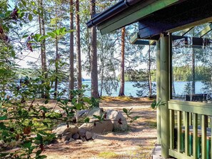 A wooden deck overlooking a lake with trees and rocks in the foreground. - Purjeranta by Interhome (Pertunmaa)
