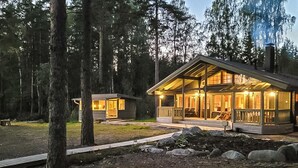 Eine Lodge mit großer Veranda und überdachter Terrasse, umgeben von einem Wald.