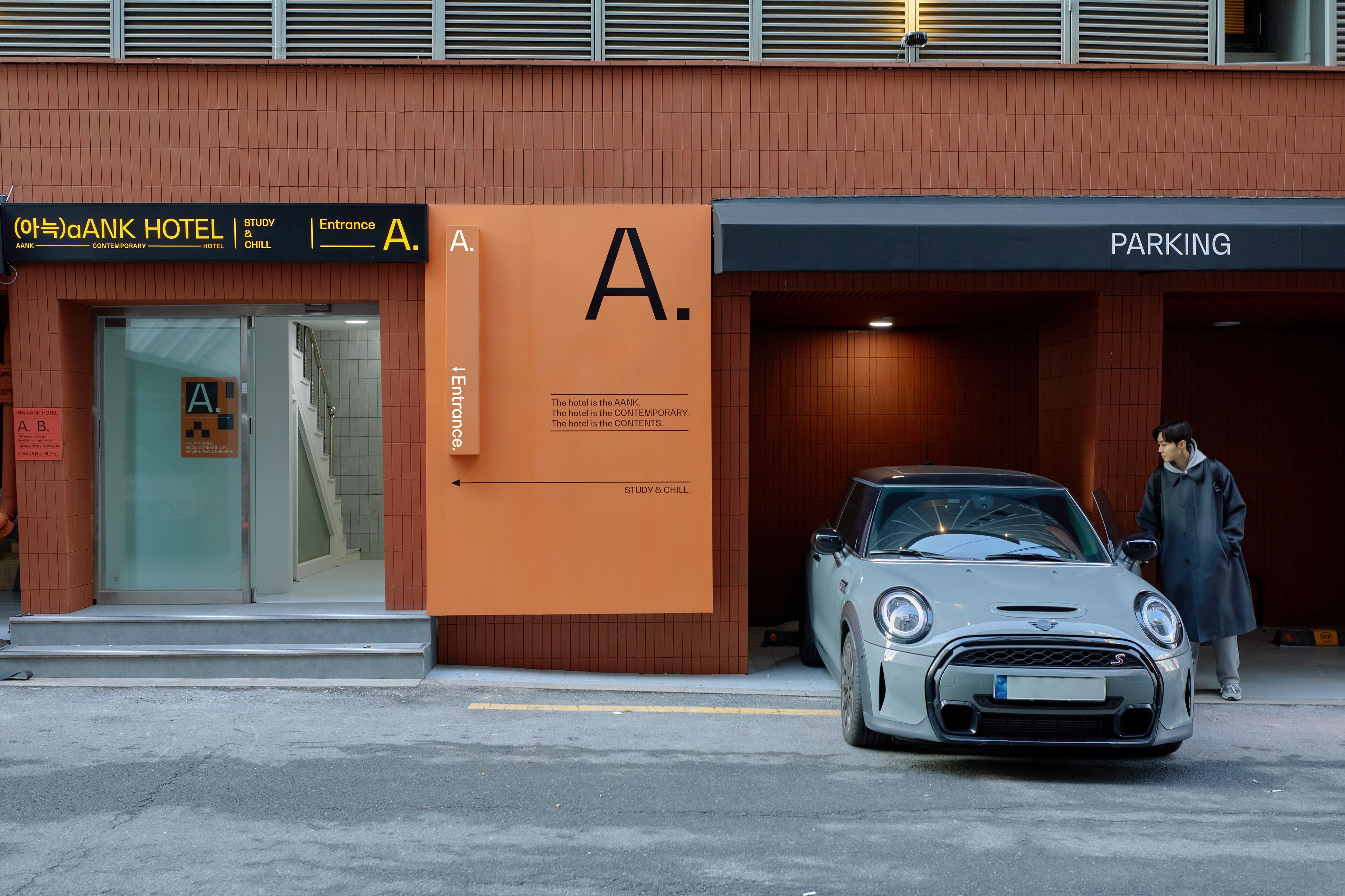 A building with a sign reading "ANK HOTEL" and "PARKING" on the right.