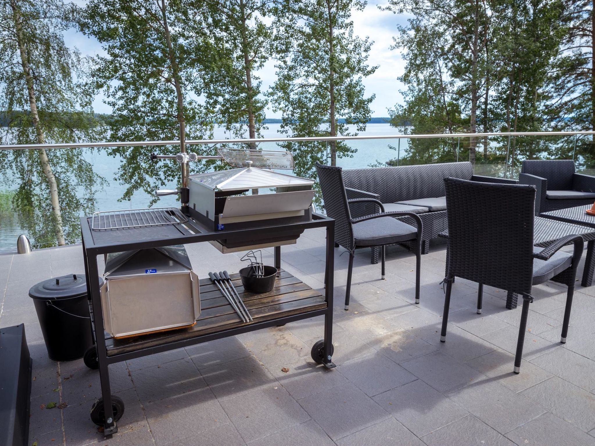 An outdoor patio with a grill, seating, and a view of the lake.