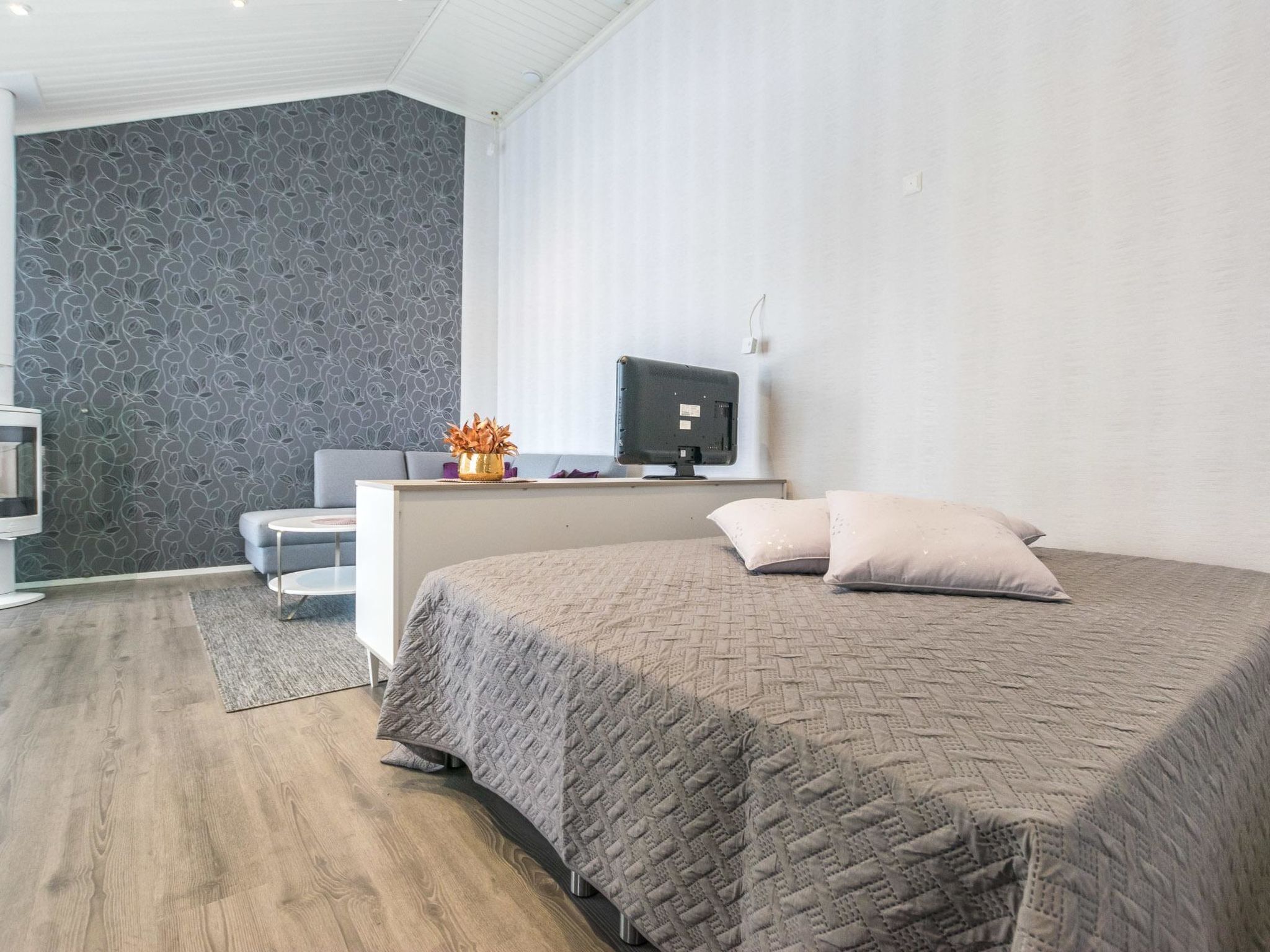 A modern bedroom with a large bed, a desk with a computer, and a TV.