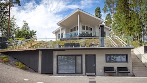 Een modern huis met twee verdiepingen, een overdekt terras en een trap naar de bovenverdieping.