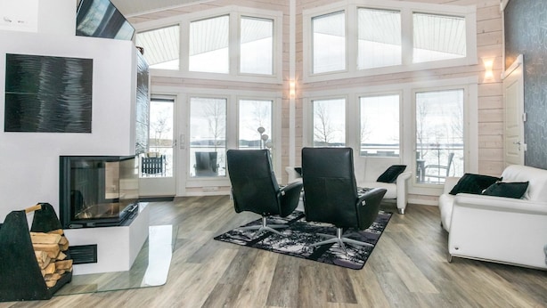 Een ruime woonkamer met een open haard, grote ramen en een modern design.