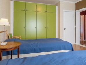 Een kamer met een bed, een stoel, een tafel en een groene garderobe.