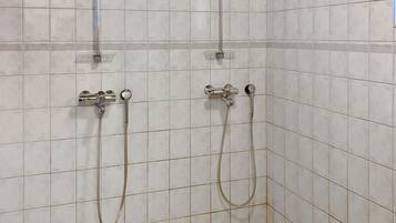 Un espacio de ducha con dos cabezales y pared de azulejos.