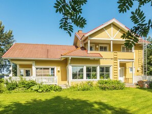 A two-story house with a red-tiled roof, large windows, and a white porch.