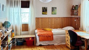 A cozy bedroom with a wooden bunk bed, a desk with a chair, a globe, and bookshelves.