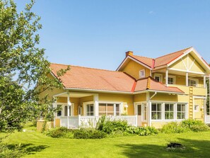A two-story house with a red-tiled roof, a balcony, and a well-maintained lawn.
