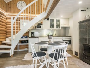 A modern kitchen with white cabinetry, a built-in microwave, and a dining area with a white table and chairs. - Kaislaranta by Interhome (Suonenjoki)