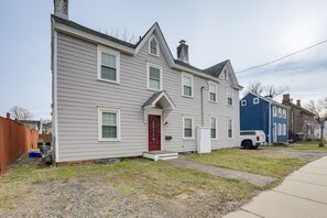 Une maison à deux étages avec une porte rouge, un petit porche à l’avant et une allée.