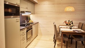 Een moderne keuken met houten paneelwanden, roestvrijstalen apparatuur en een eethoek met een tafel voor twee personen.