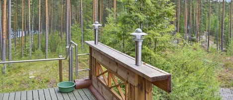 Een houten terras met een leuning, een groene schaal en een metalen lantaarnpaal.