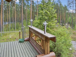 A wooden deck with a railing, a green bowl, and a metal lamp post. - Villa tunturitervakko by Interhome (Liperi)