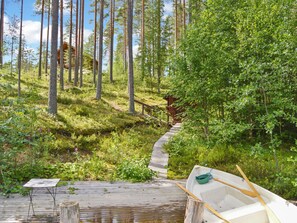 A wooden deck leading to a cabin in a forested area with a small boat on the right. - Villa tunturitervakko by Interhome (Liperi)