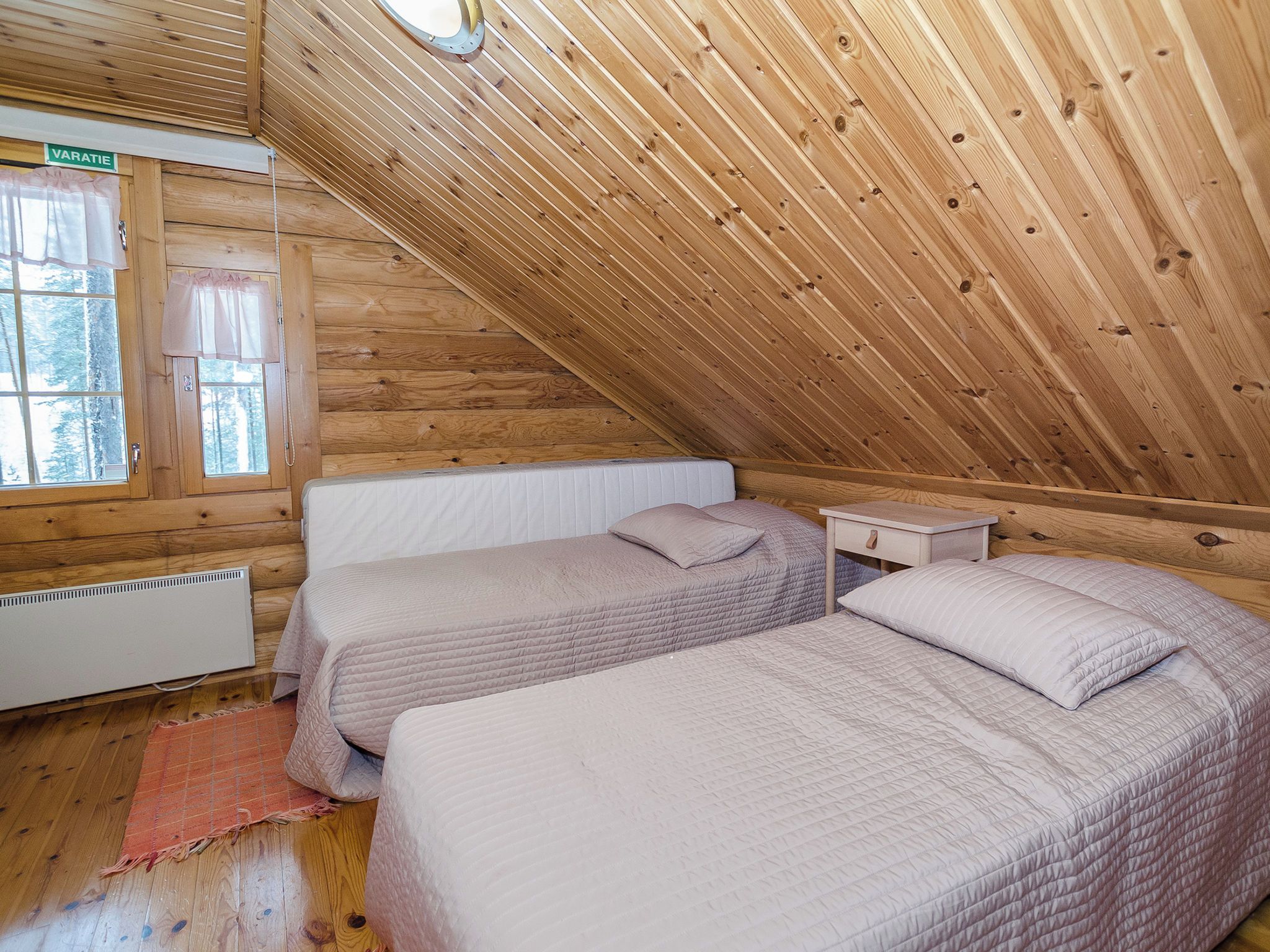 Una cabaña de madera con dos camas, una ventana y un radiador.