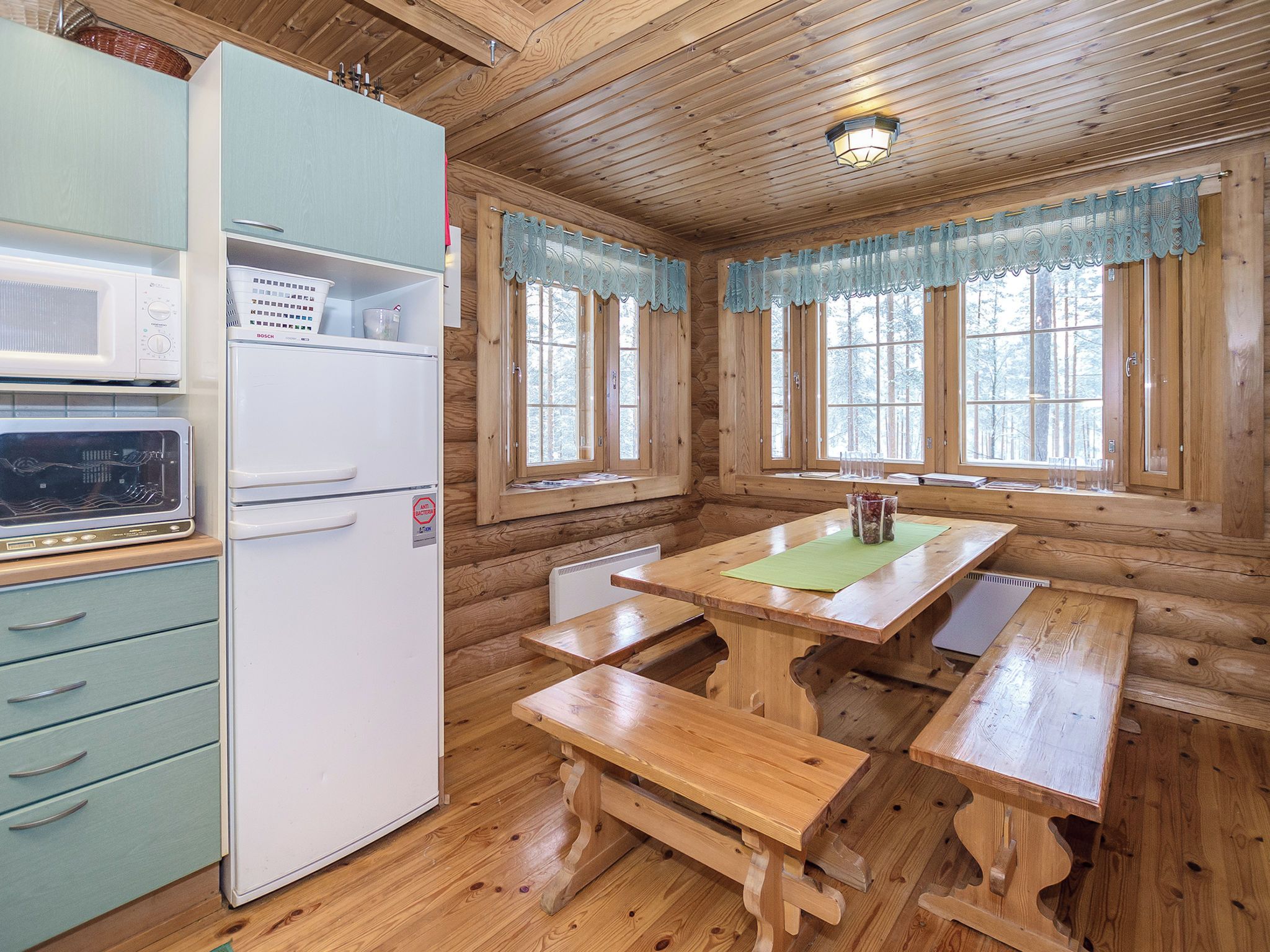 A cabin interior with a kitchenette, wooden benches, and large windows.
