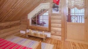 Un chalet confortable en rondins de bois, avec un intérieur en bois, un escalier doté d’une balustrade en dentelle, un drapeau suisse et une porte avec une fenêtre.