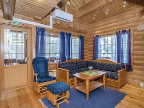 A log cabin interior with a wooden bench, a chair, a table, and a sofa.