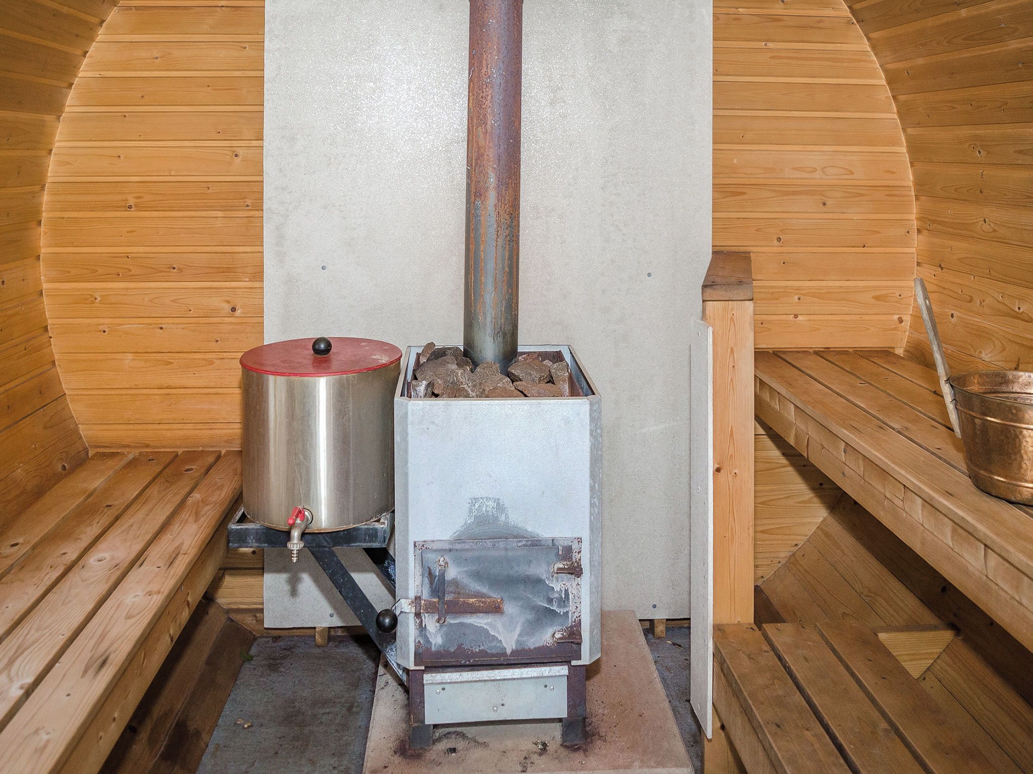 En vedeldad kamin med en metallbehållare och ett metallrör.