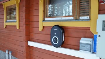 Une cabane en bois avec une fenêtre, un carillon et un coffret de raccordement électrique.