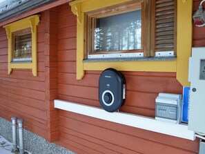 Une cabane en bois avec une fenêtre, un carillon et un coffret de raccordement électrique.
