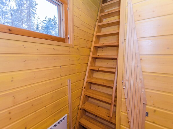 Un interior de madera con una ventana, una escalera y un radiador.