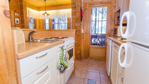 Une cuisine de taille réduite, dotée de meubles de rangement en bois, d’une cuisinière, d’un évier et d’un réfrigérateur.