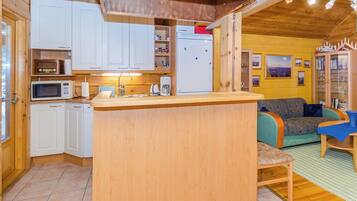A compact kitchen with white cabinets, a microwave, and a refrigerator.