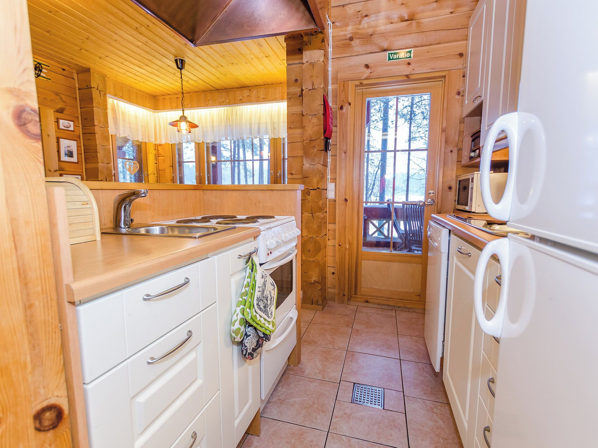 A compact kitchen with wooden cabinets, a sink, a stove, and a refrigerator.