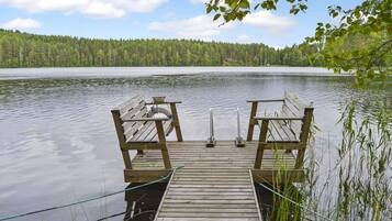 A wooden dock extending into a calm lake, surrounded by dense forest.