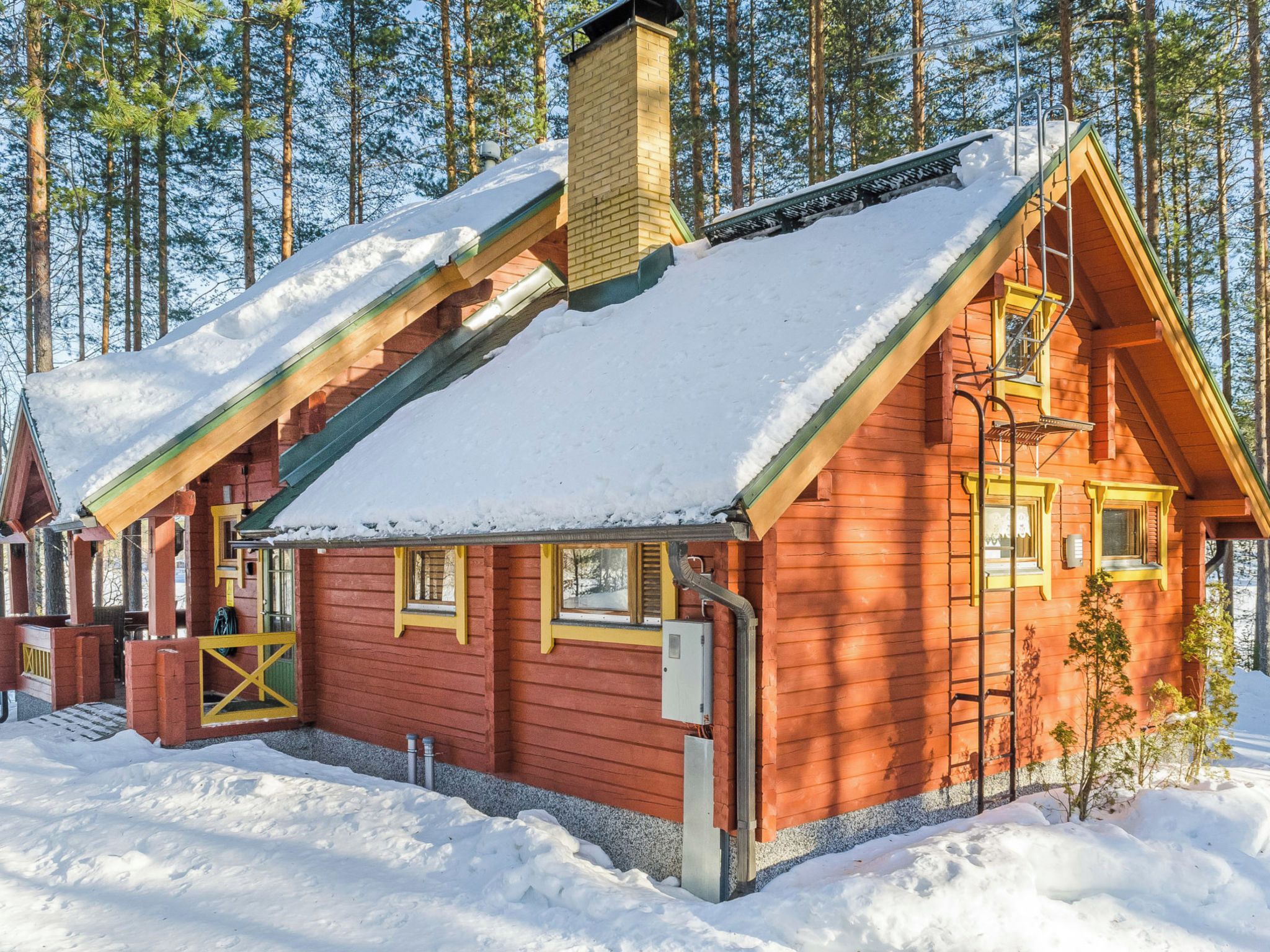 A log cabin with a steeply pitched roof, a chimney, and a small porch with a yellow gate.