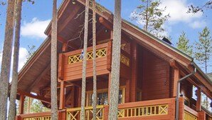 Une cabane en bois dotée d’un balcon, entourée d’arbres.