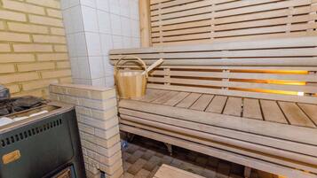 A sauna with wooden benches, a brick wall, and a tiled floor.