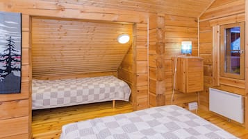 Une petite cabane en bois avec deux lits, une fenêtre et un radiateur.