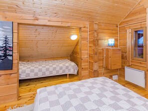 A small wooden cabin with two beds, a window, and a radiator. - Villa käpytikka by Interhome (Liperi)